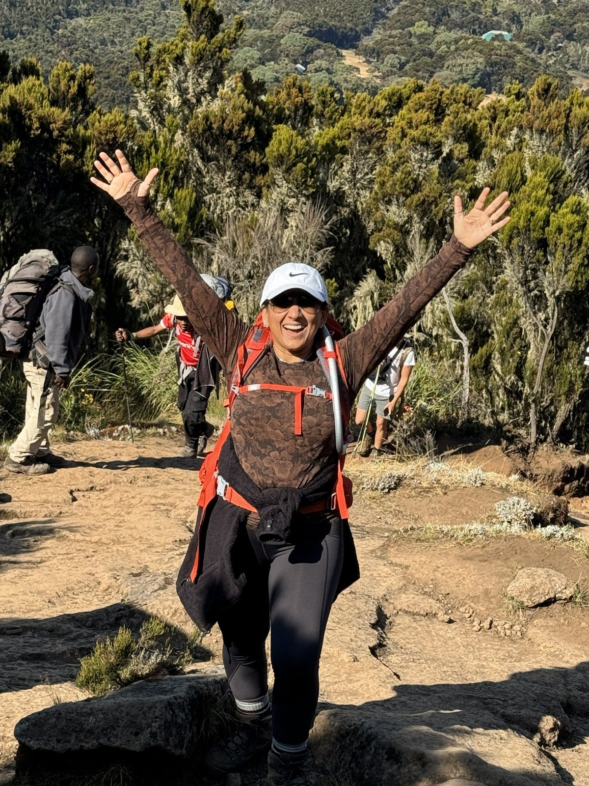 Rashmi with arms raised on a Kilimanjaro trail